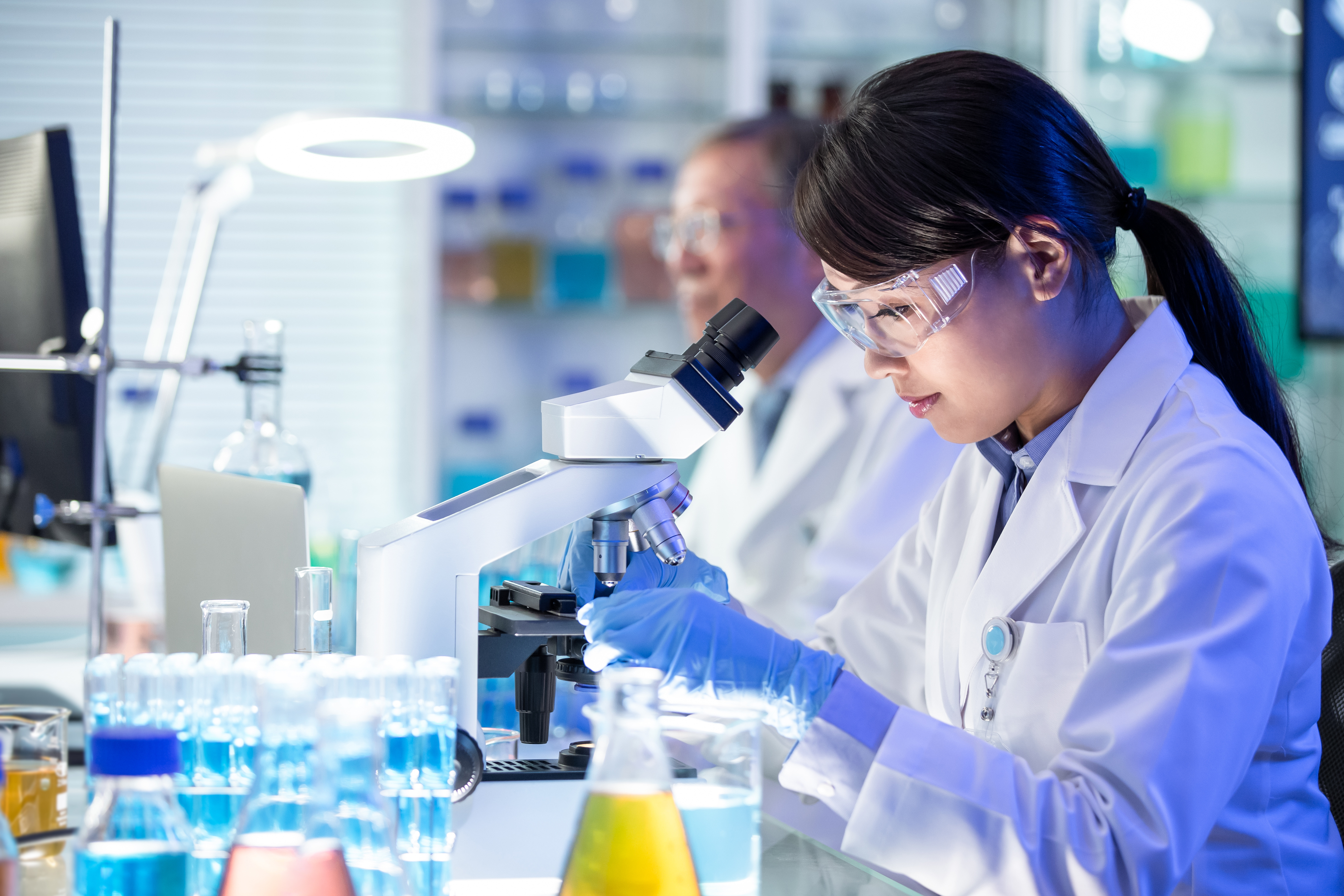 Scientists working in a laboratory, using a microscope and handling glassware during research